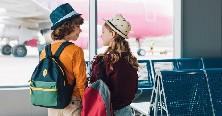 Kinderen voor een vliegtuig, die wachten om op reis te gaan