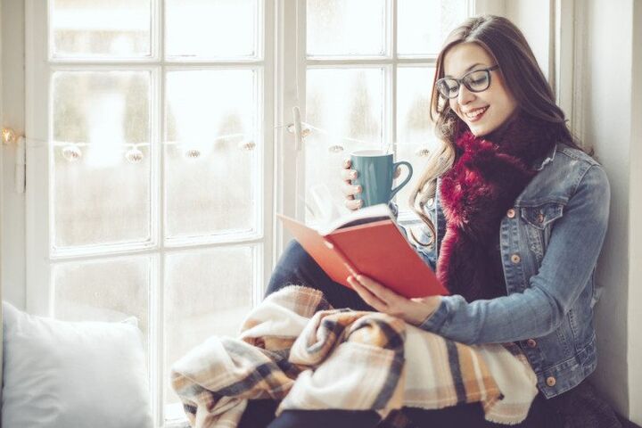 vrouw leest boek in raam